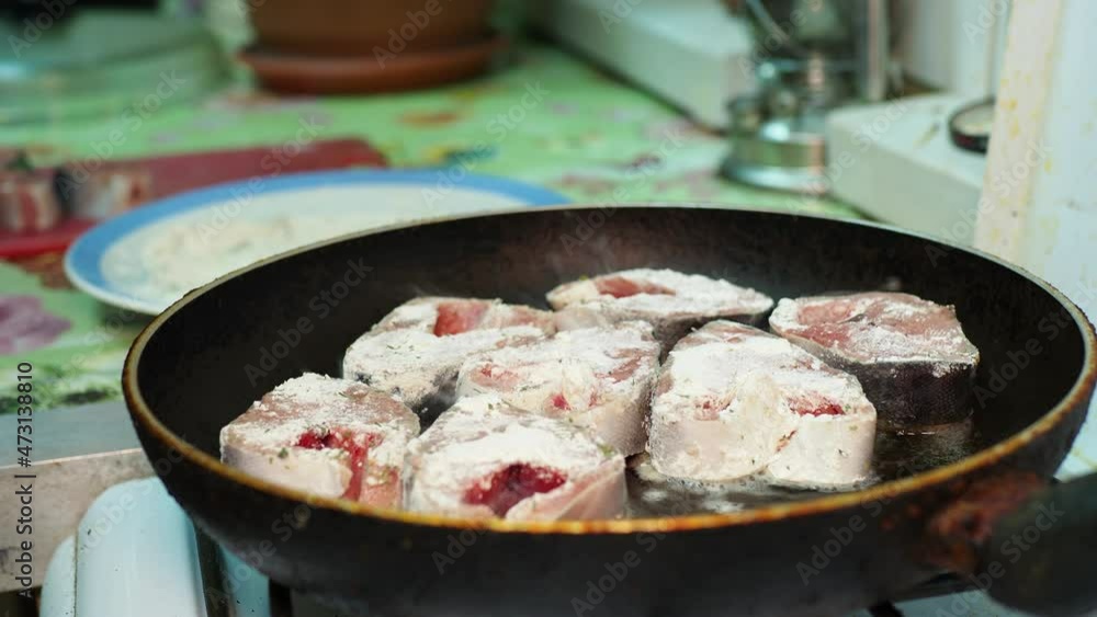 Asian cuisine. A woman rolls pieces of salmon in flour and puts them in a frying pan. Siberia. Close-up. Asian cuisine. A woman rolls pieces of salmon in flour and puts them in a frying pan. Siberia. Close-up.