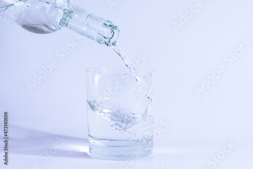Pour water from the bottle into a glass. Isolated on white background.