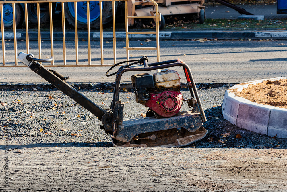 worker compresses sand for paving slabs with special working tool