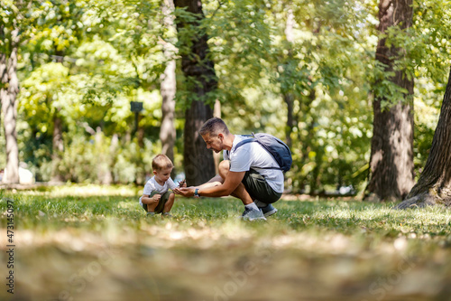Research and learning in nature. A family in the woods spends time together. The child and father squat and add leaves to each other as they explore nature. Learning through play in the park
