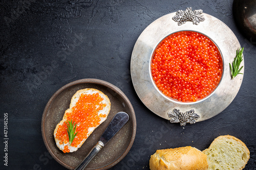 Delicious red caviar in vintage plate, top view, dark background photo