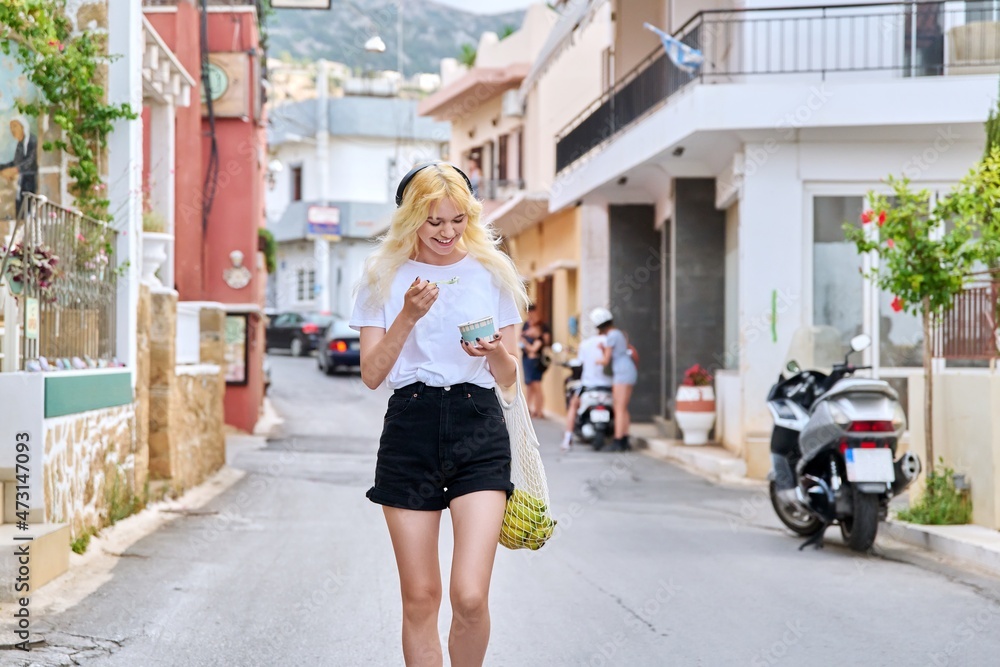 Young teenage blonde walking down the street of summer European tourist city
