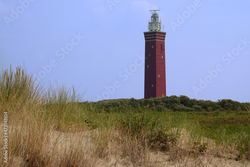 Red lighthouse and green meadow against a blue gray sky. Ouddorp, Netherlands.