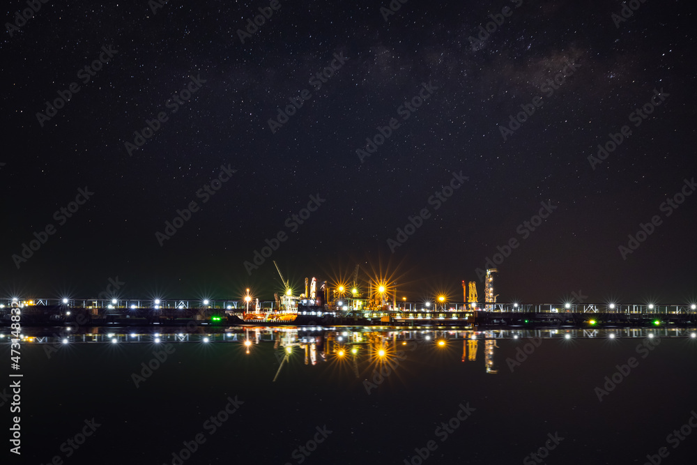 Oil ship tanker at dusk waiting for load/unload at loading dock from refinery for transportation. starlight background