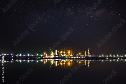 Oil ship tanker at dusk waiting for load/unload at loading dock from refinery for transportation. starlight background