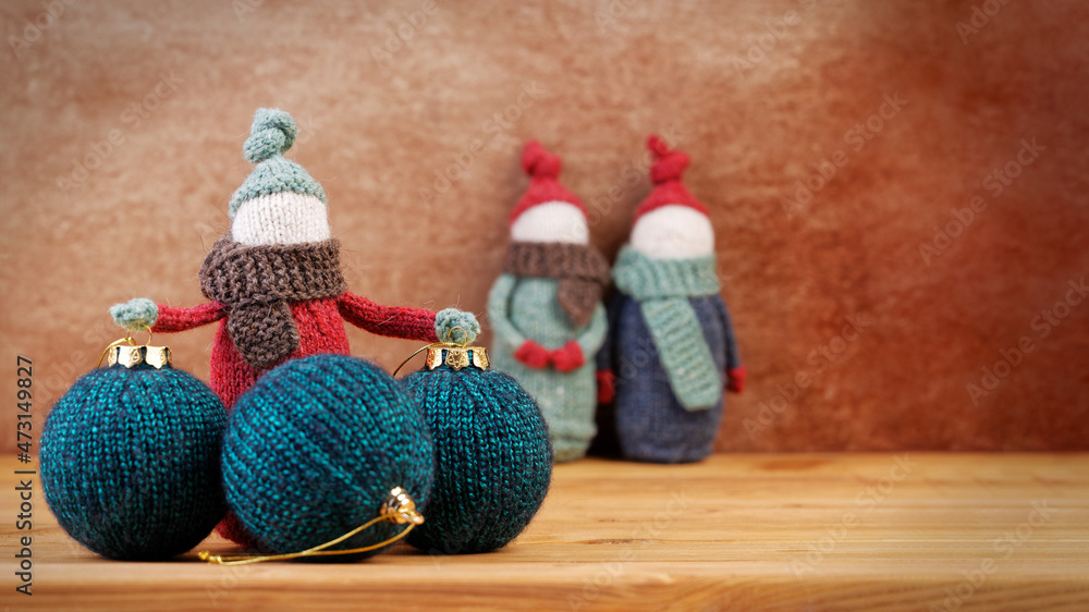 Handmade knitted gnomes with Christmas balls on a wooden table. Christmas concept. Copyspace.