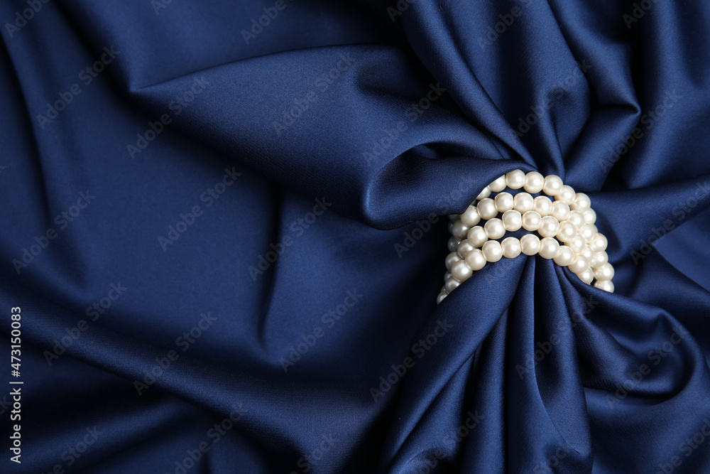 Beautiful pearls with dark blue silk as background, space for text Beautiful pearls with dark blue silk as background, space for text