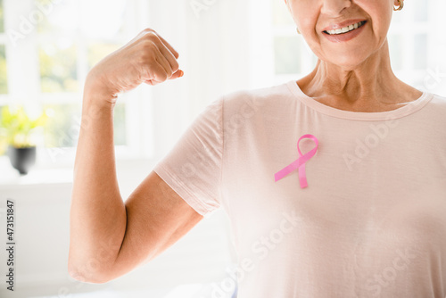 Mature senior elderly strong woman in pink t-shirt with pink ribbon supporting fighting for breast cancer movement. Togetherness, oncology recovery concept photo