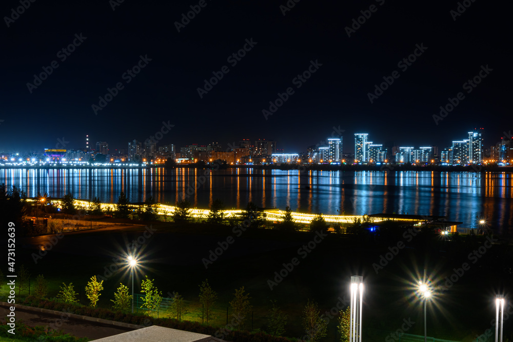 Fototapeta premium Illuminated buildings on the river bank