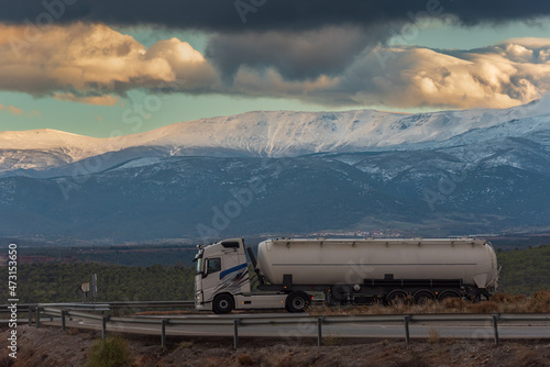 Truck with silo semi-trailer for the transport of powders with Sierra Nevada in the background.