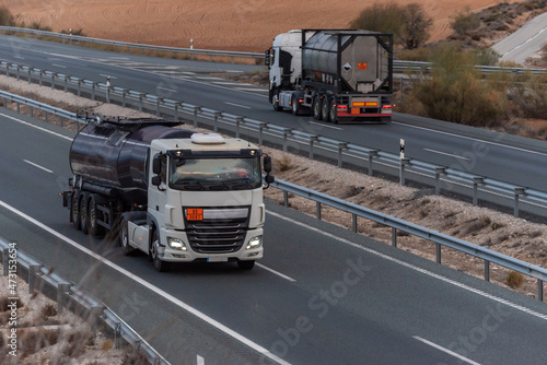 Dangerous goods tanker trucks traveling in opposite directions on the highway.