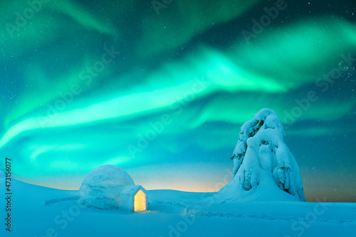 Aurora borealis. Northern lights in winter mountains. Wintry scene with glowing polar lights and snowy igloo. Landscape photography