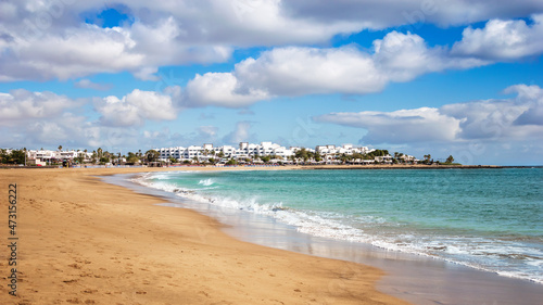 View of Playa de los Pocillos beach in Puerto del Carmen town  Lanzarote. Panorama of sandy beach with turquoise ocean water  white houses of tourist resort on Canary Islands  Spain