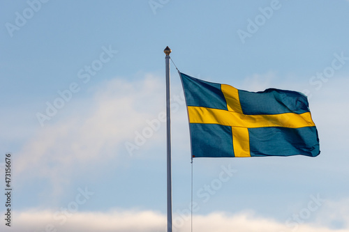 Swedish flag on a pole flying in the wind. Space for text