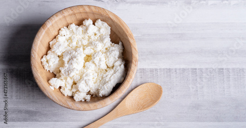 Requesón en cuenco de madera, fondo gris claro.