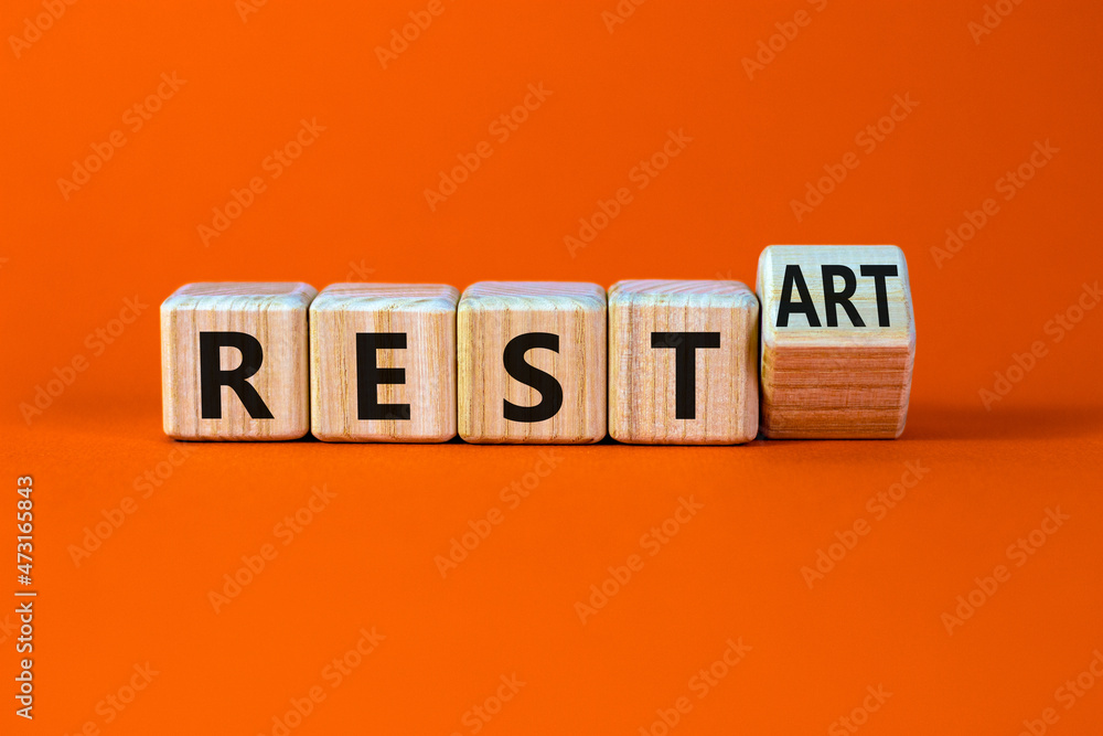 Rest and restart symbol. Turned a wooden cube and changed the word rest to restart. Beautiful orange table, orange background, copy space. Business, rest and restart concept. - obrazy, fototapety, plakaty 