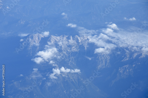 Beautiful window view of blue sky, fluffy clouds and Alps mountains from passenger seat on airplane. Travel and air transportation. Holidays © Oleksandra