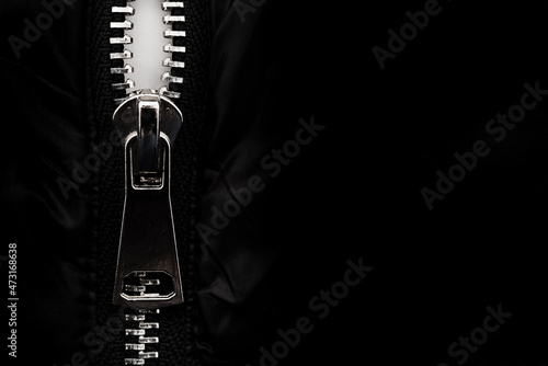 White lock with a zipper on clothes, jacket, jacket close-up on a black background. Lightning.