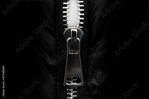 White lock with a zipper on clothes, jacket, jacket close-up on a black background. Lightning.