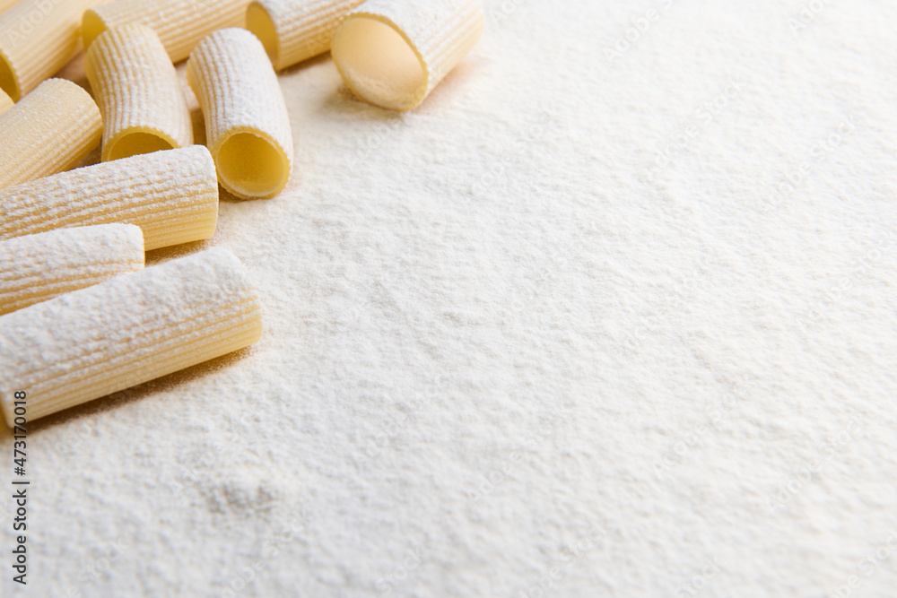Whole wheat Italian pasta - uncooked tortiglioni- in the corner of a white coloured background with copy space for food advertisement Whole wheat Italian pasta - uncooked tortiglioni- in the corner of a white coloured background with copy space for food advertisement