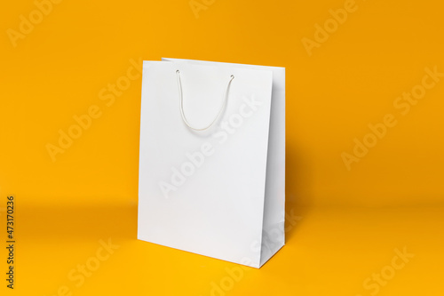 Mockup of white shopping bag isolated over orange paper background. side view