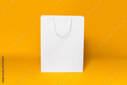 Mockup of white shopping bag isolated over orange paper background. straight view