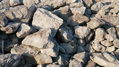 Stone and rock - close up. Heap of of crushed pieces used as natural building material. Texture of large broken boulders - pile of raw shattered aggregate from a quarry. Desolate mountain or hill.