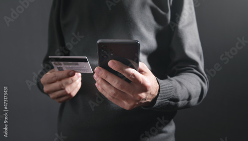 Man using smartphone and holding credit card.