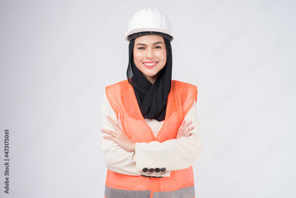 A muslim woman engineer wearinng a protective helmet over white backgroud studio