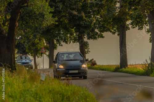 Passenger cars on alley road with leaf trees in sunset summer evening © luzkovyvagon.cz