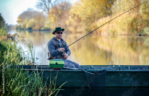 Fisherman sitting in the boat and angling on the river. Sport and recreation concept
