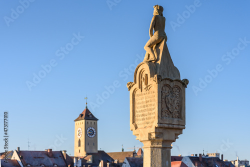 Brückmandl, auf der steinernen Brücke in Regensburg mit Stadt Silhouette im Hintergrund mit Rathausturm photo