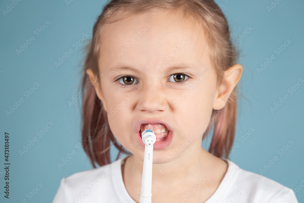 Smiling little caucasian girl brushing teeth Standing Over blue Background Smiling little caucasian girl brushing teeth Standing Over blue Background