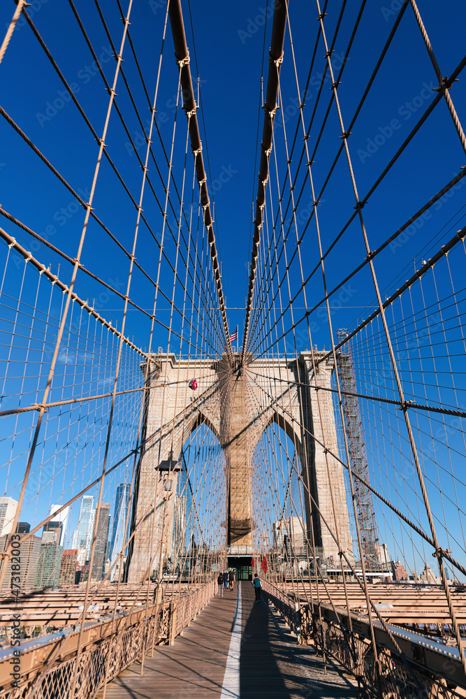 Fototapeta premium New York, USA - 2021: Brooklyn Bridge, built in 1883, was the first fixed crossing of the East River. Photo taken during the day with blue sky and view to the beautiful Manhattan.