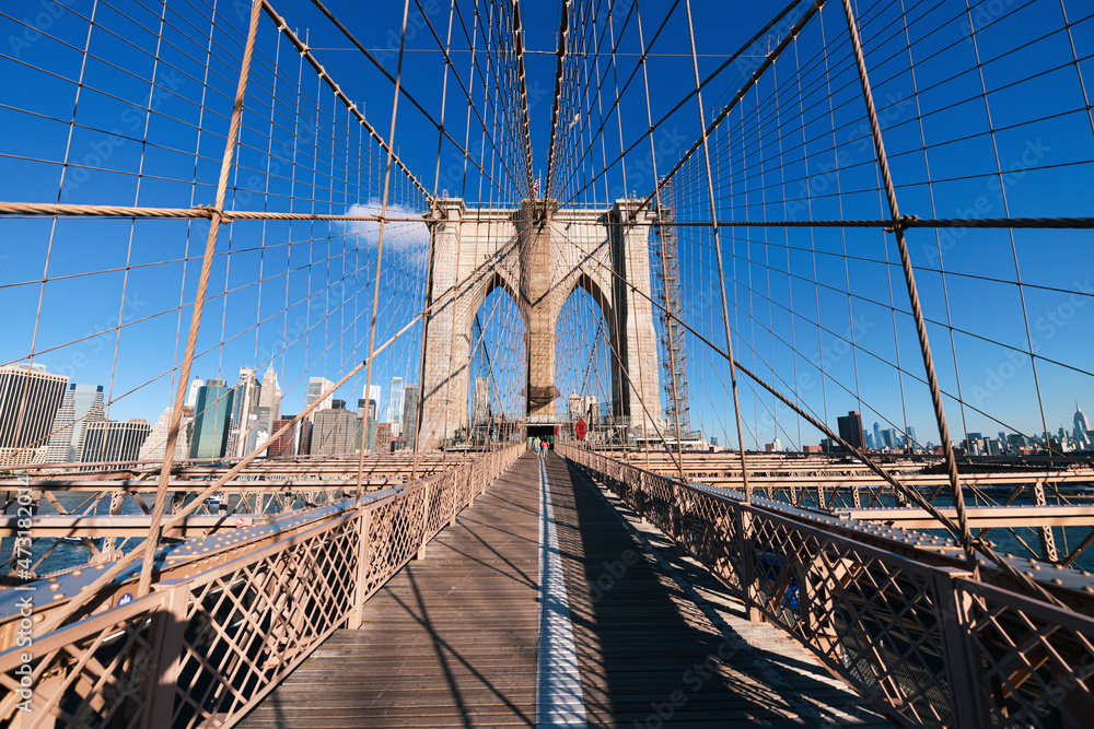 Fototapeta premium New York, USA - 2021: Brooklyn Bridge, built in 1883, was the first fixed crossing of the East River. Photo taken during the day with blue sky and view to the beautiful Manhattan.