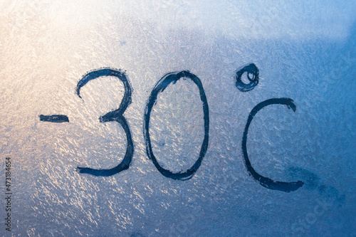 -22 degrees Fahrenheit or -30 Celsius number lettering on icy glass covered with ice and frost. The concept of extreme cold weather.