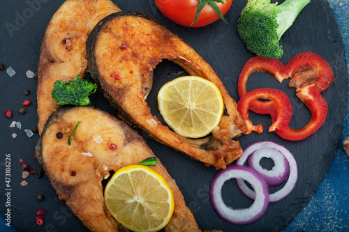 Christmas carp, Fried carp fish slices on a black plate.  Fried golden crust fish fillets with  lemon and vegetables, top view.