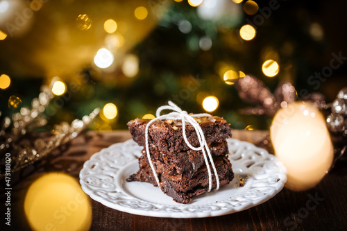 Chocolate brownies wrapped in group as a present in front of Christmas tree with Christmas lights in festive atmosphere and decoration
