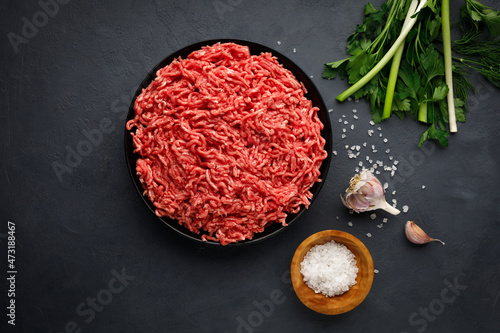 Minced meat, spices and herbs on black background. Top view. photo
