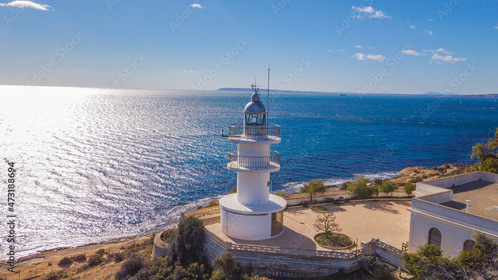 Faro del Cabo de las Huertas en Alicante , vista aérea en un día luminoso y con el mar peinado por el fuerte viento de poniente y con un fuerte color azul del mar.