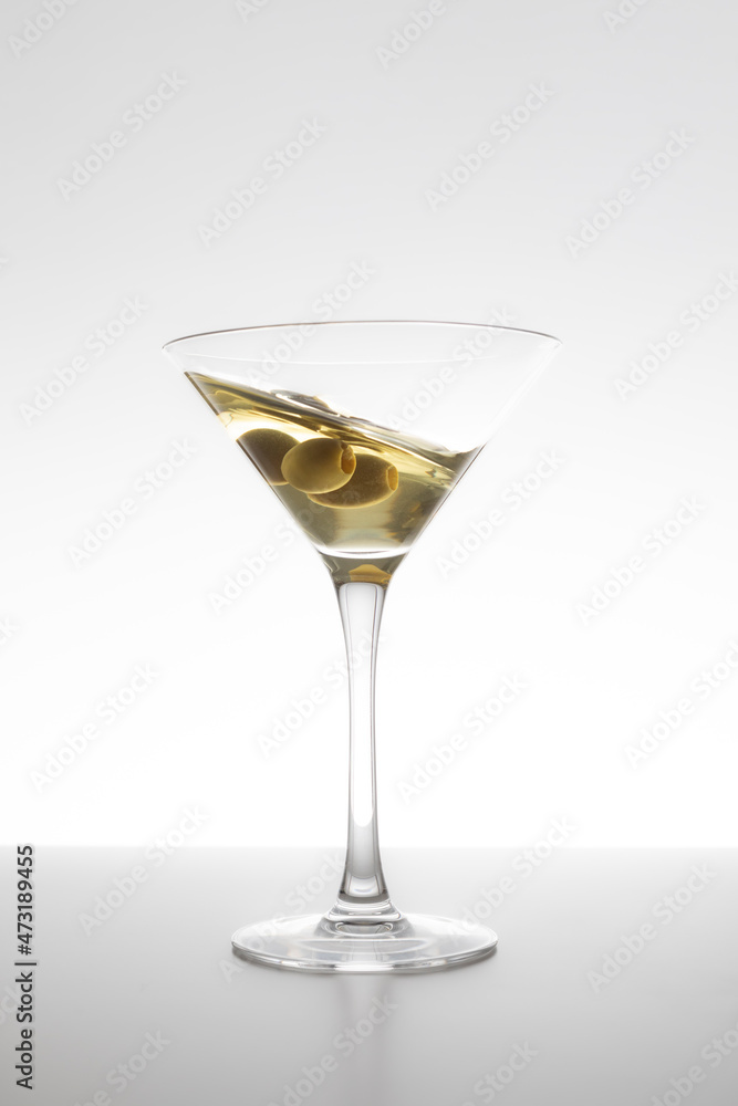 Vermouth glass in motion with olives on a white background