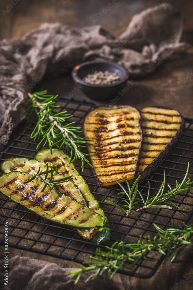 Grilled zucchini and eggplant slices on a cooling rack on wooden background, vertical