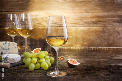 Composition of grape, cheese and white wine on wooden background. Copy space