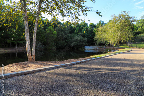 a stunning shot of a lake in the park surrounded by lush green and autumn colored trees reflecting off the water with a smooth footpath and blue sky at Garrard Landing Park in Alpharetta Georgia USA photo