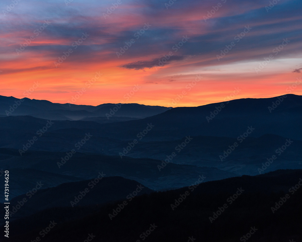 Amazing landscape in the mountains. View of mountains silhouettes and colorful sky at distance in  twilight.