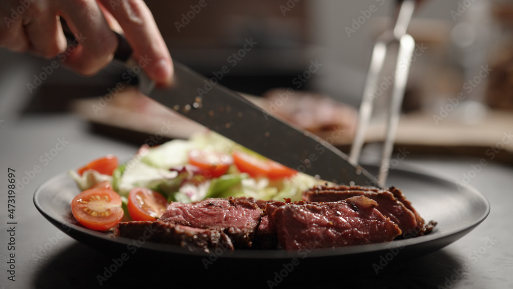 put new york steak slices on black plate with mixed greens and cherry tomatoes put new york steak slices on black plate with mixed greens and cherry tomatoes
