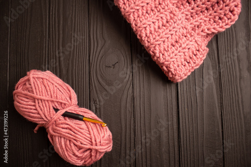 pink hat and crochet yarn on dark background © Tetiana