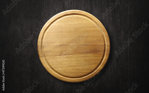 Wooden pizza or bread cutting board on dark background. Top view.