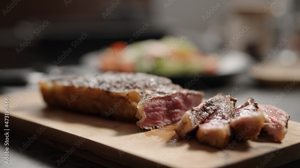 sliced new york steak on olive wood board
