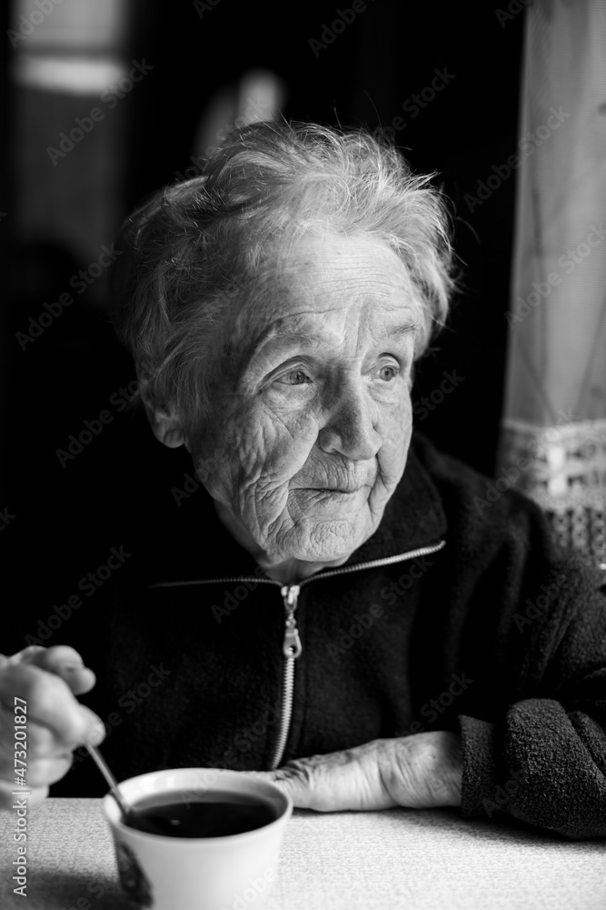 An old woman with a cup of tea. Black and white photo. An old woman with a cup of tea. Black and white photo.